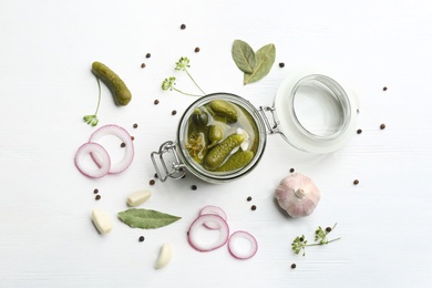 Photo of Glass jar of pickled cucumbers on white wooden table, flat lay
