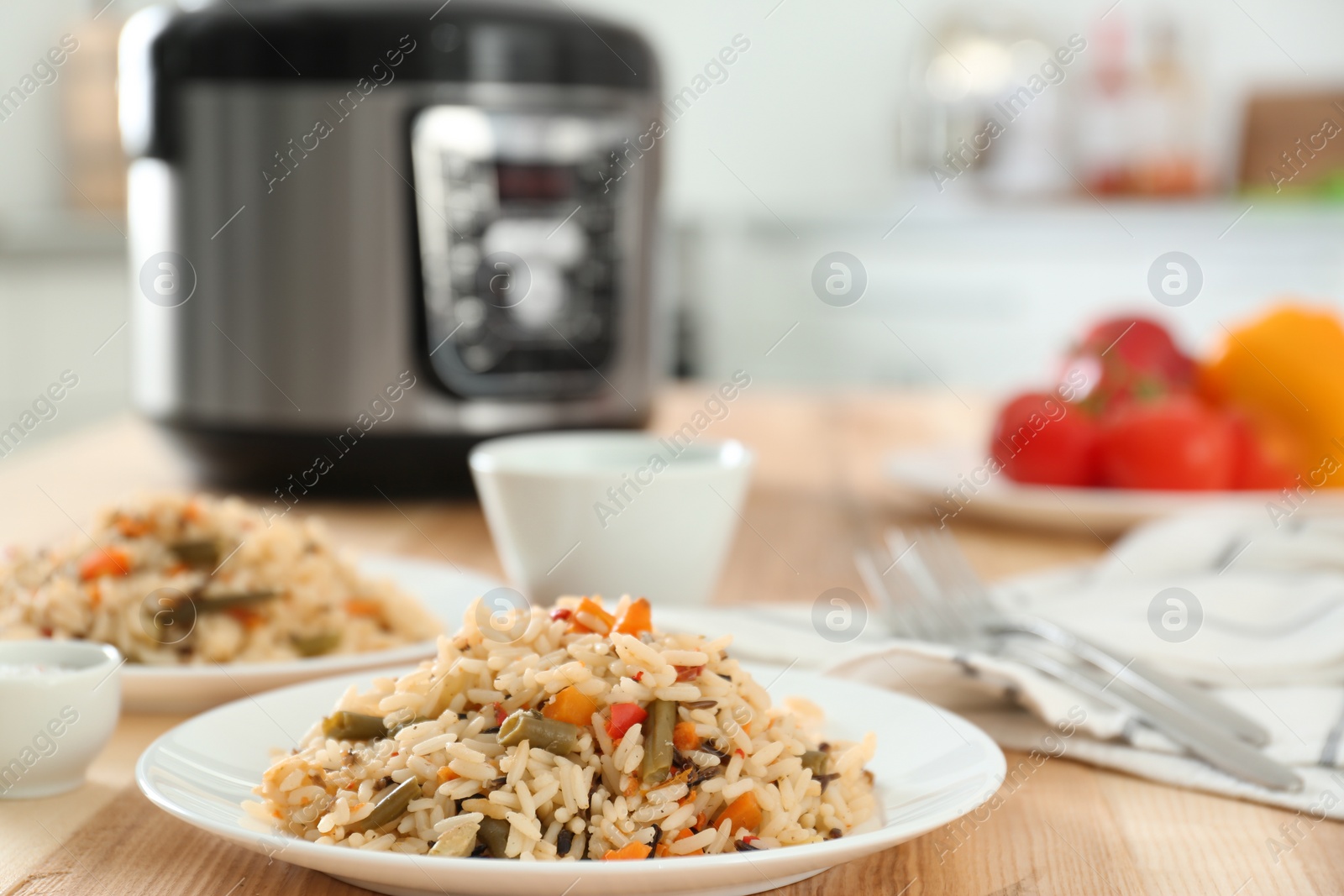 Photo of Delicious rice with vegetables and multi cooker on wooden table