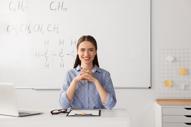 Photo of Young chemistry teacher at table in classroom