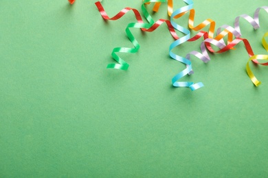 Colorful serpentine streamers on green background, flat lay. Space for text