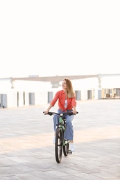 Young woman riding bicycle in city on sunny day