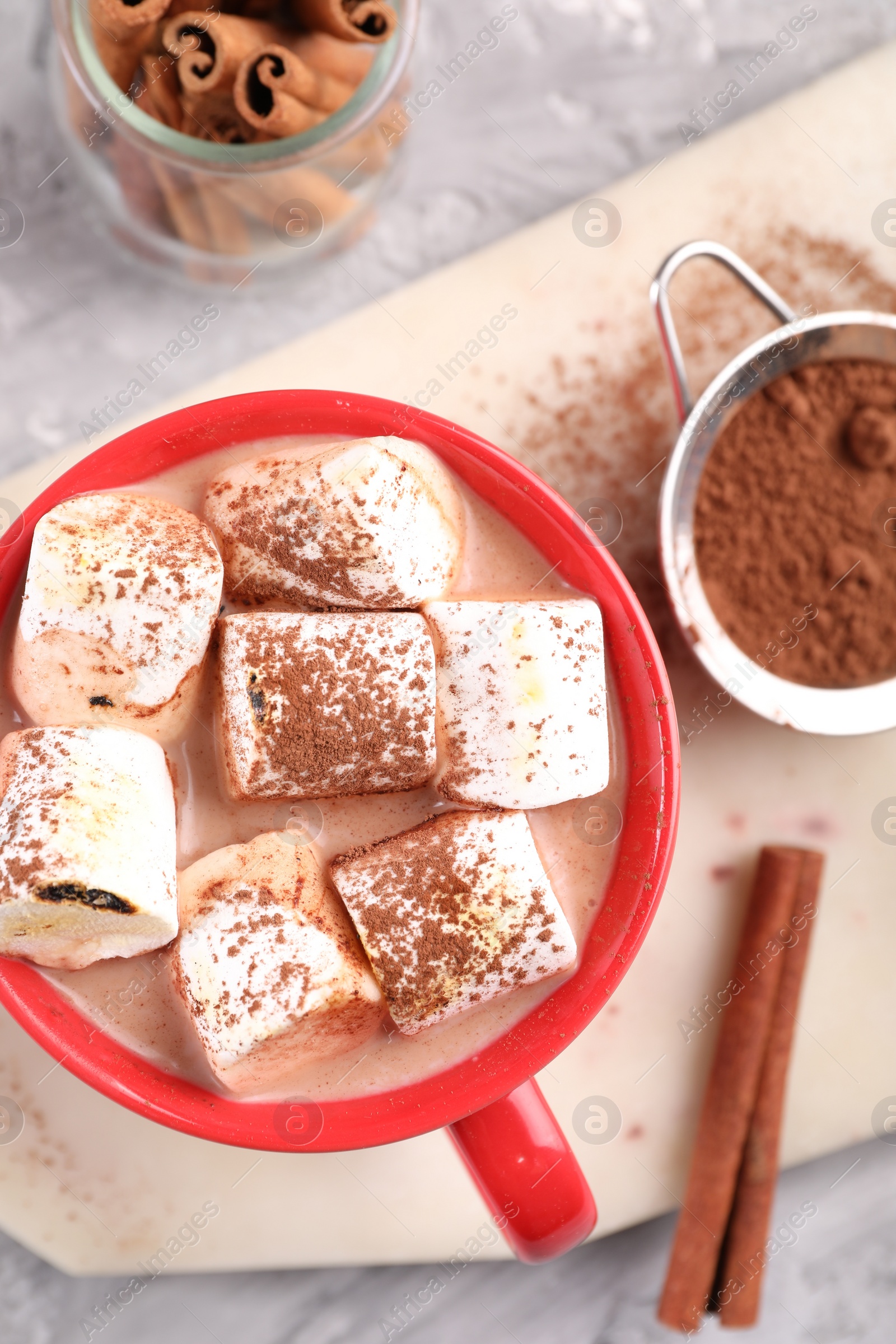 Photo of Cup of aromatic hot chocolate with marshmallows, cocoa powder and cinnamon sticks on table, flat lay