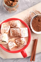 Cup of aromatic hot chocolate with marshmallows, cocoa powder and cinnamon sticks on table, flat lay