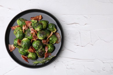 Photo of Delicious roasted Brussels sprouts, bacon and rosemary on white textured table, top view. Space for text