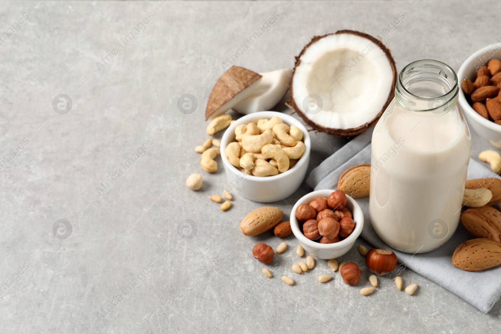 Photo of Vegan milk and different nuts on light table. Space for text