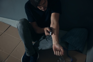 Photo of Male drug addict making injection near grey wall