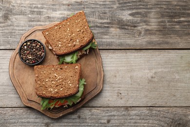 Photo of Delicious sandwiches with tuna, vegetables and peppercorn on wooden table, top view. Space for text
