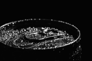 Aluminum can of beverage covered with water drops on black background, closeup