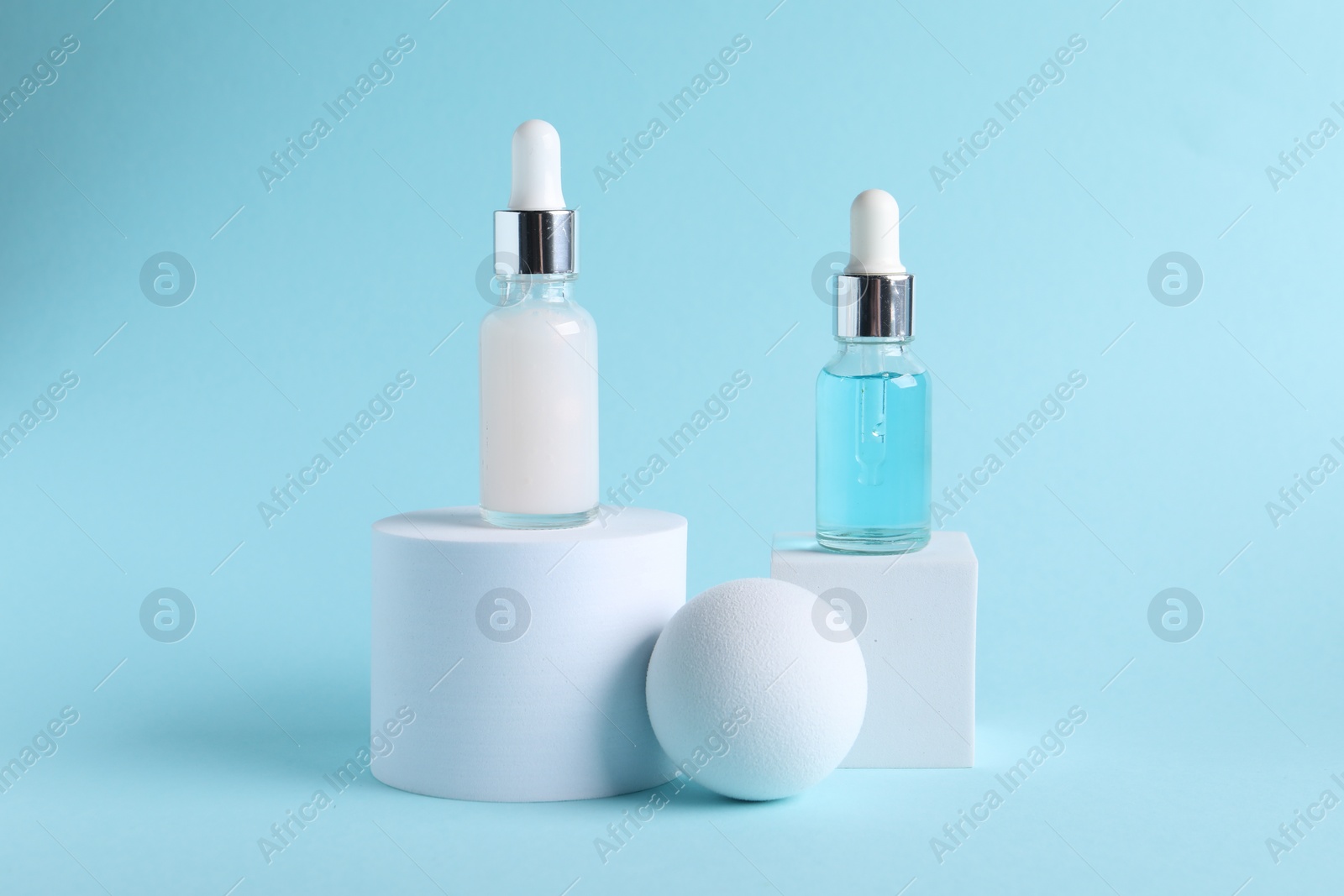 Photo of Stylish presentation of cosmetic serum on light blue background