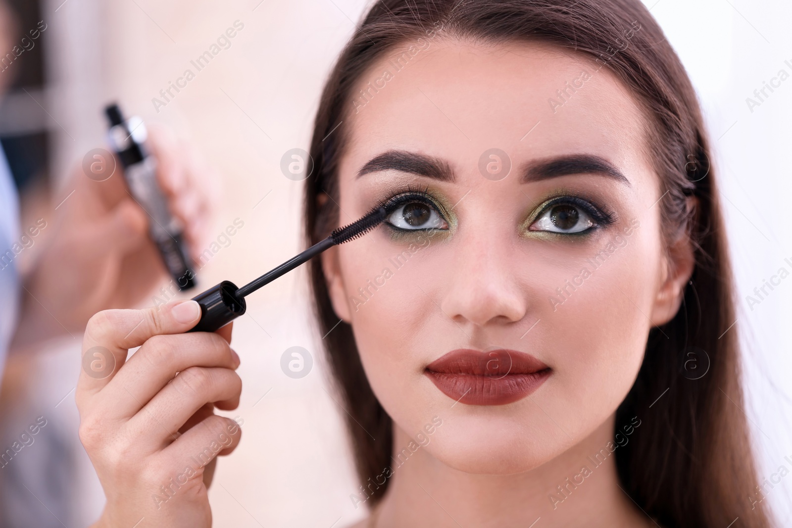 Photo of Professional visage artist applying makeup on woman's face in salon, closeup