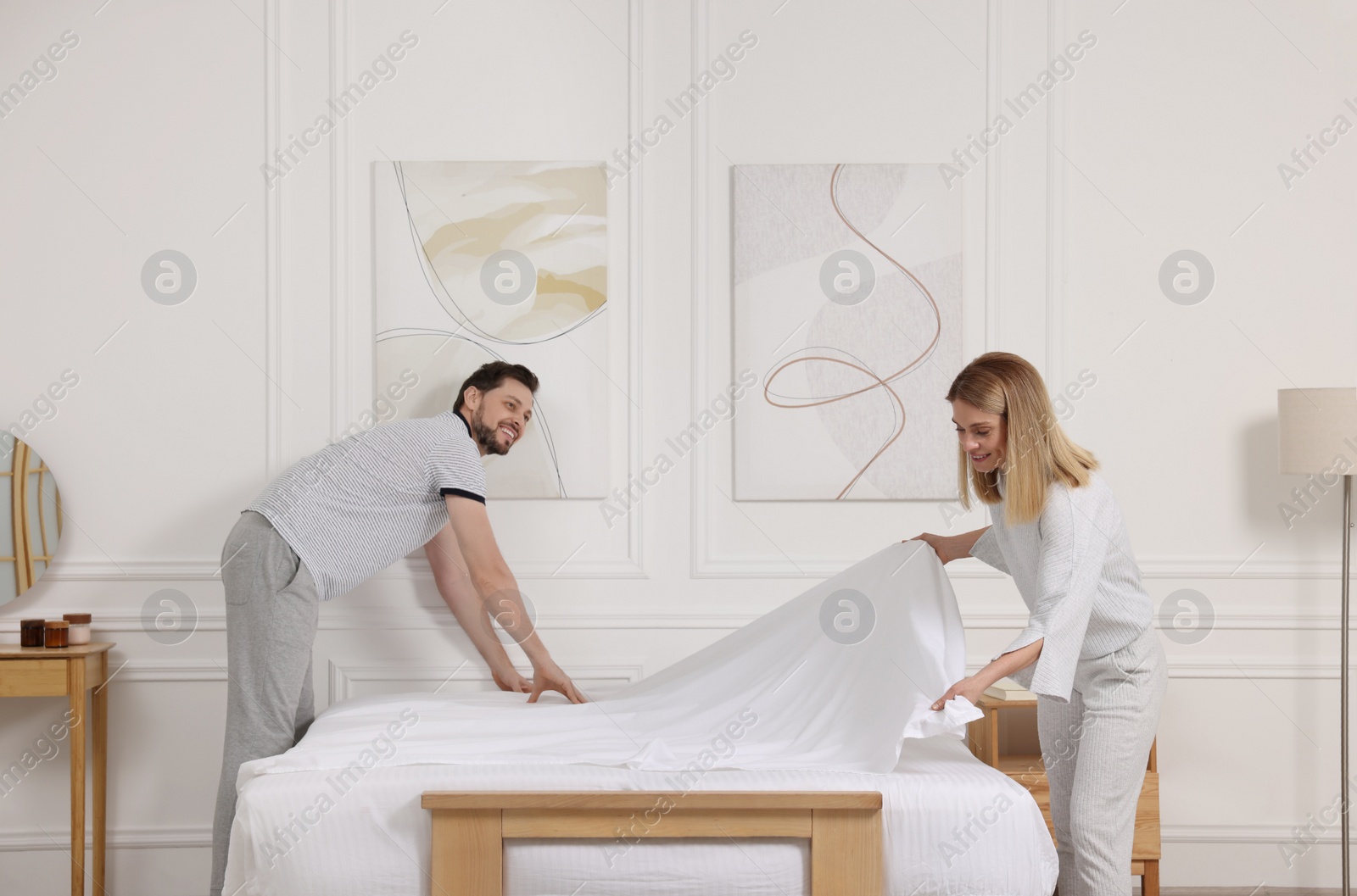 Photo of Couple changing bed linens at home. Domestic chores