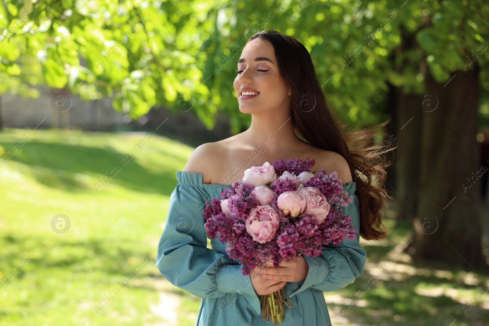 Photo of Beautiful woman with bouquet of spring flowers in park on sunny day