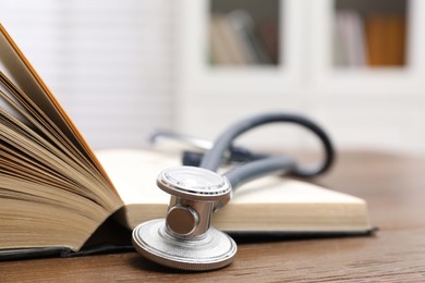 Photo of Book and stethoscope on wooden table indoors, closeup with space for text. Medical education