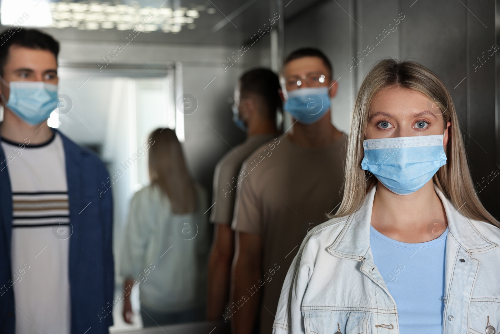 Photo of Group of people with face masks in elevator. Protective measure