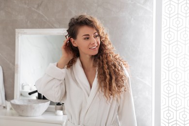 Photo of Beautiful woman wearing soft white robe in bathroom