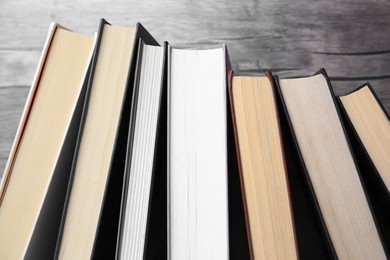 Collection of different books near wooden wall, closeup