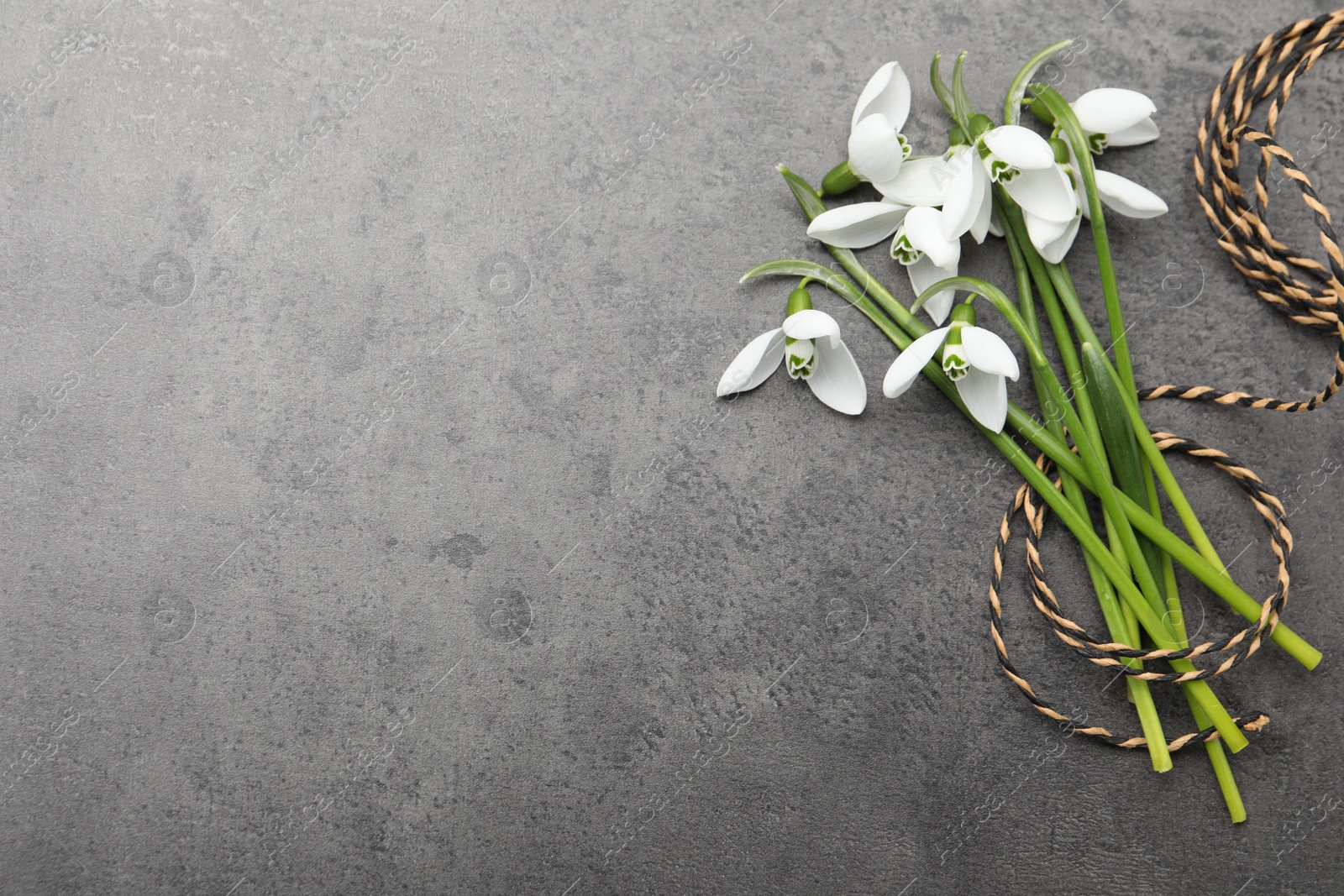 Photo of Beautiful snowdrops and twine on grey table, flat lay. Space for text