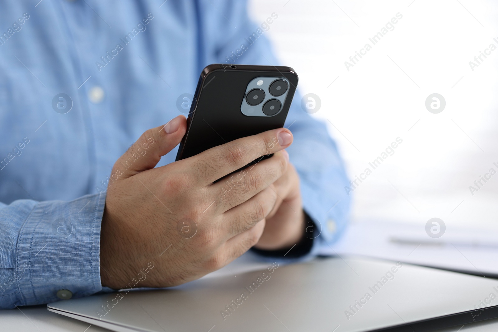 Photo of Man using smartphone at table in office, closeup