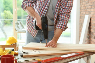 Photo of Man working with electric screwdriver indoors, closeup