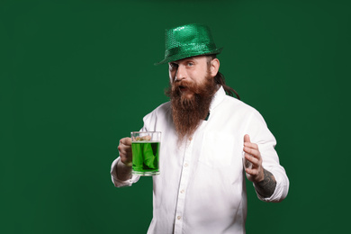 Bearded man with green beer on color background. St. Patrick's Day celebration