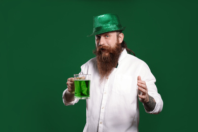 Photo of Bearded man with green beer on color background. St. Patrick's Day celebration