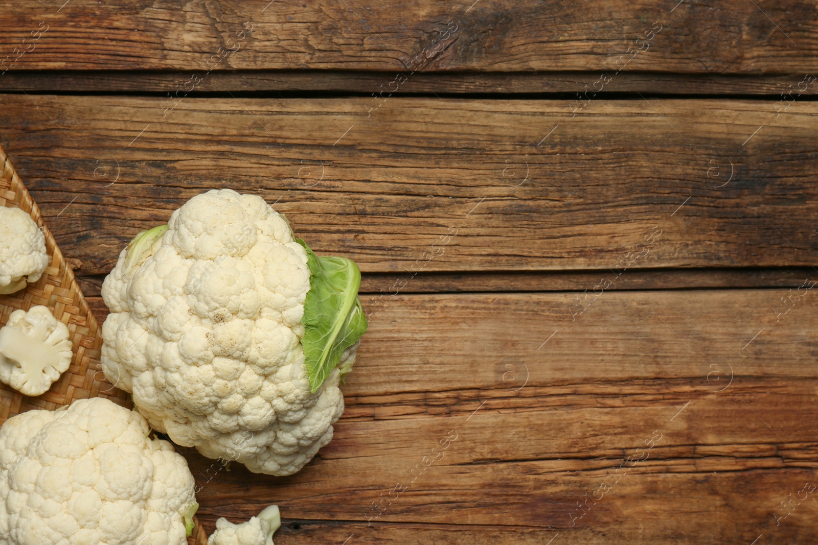 Photo of Fresh cauliflower on wooden table, top view. Space for text