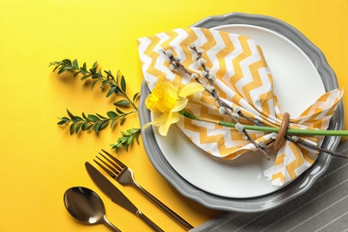 Festive Easter table setting with floral decoration on color background, top view