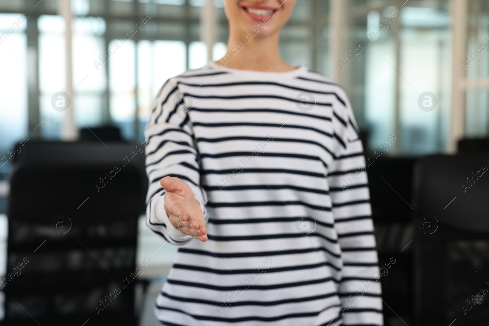 Photo of Woman welcoming and offering handshake indoors, closeup