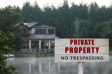 Wooden sign with text Private Property No Trespassing near house