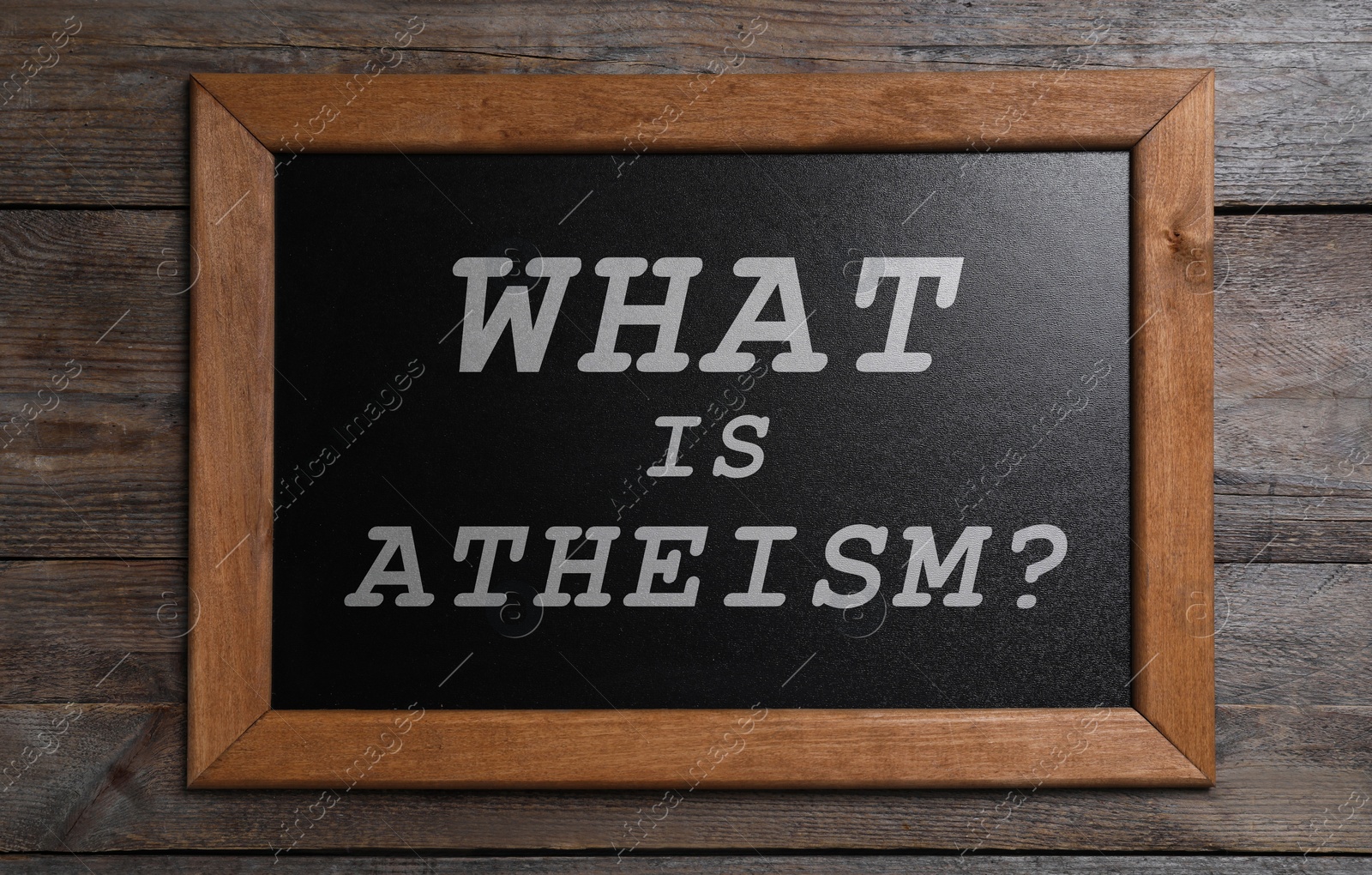 Image of Small chalkboard with phrase What Is Atheism? on wooden background