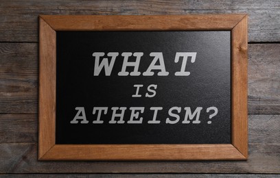 Image of Small chalkboard with phrase What Is Atheism? on wooden background