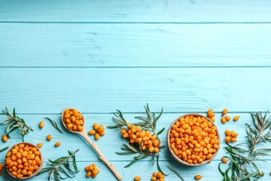 Photo of Flat lay composition with ripe sea buckthorn on light blue wooden table. Space for text
