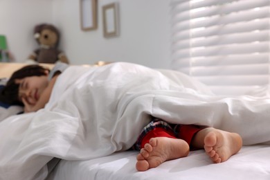 Photo of Little boy sleeping in bed at home, focus on feet
