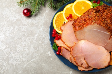 Flat lay composition with plate of Christmas ham on grey table. Space for text