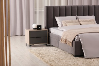 Photo of Stylish bedroom in soft light colors with comfortable bed and bedside table. Interior design