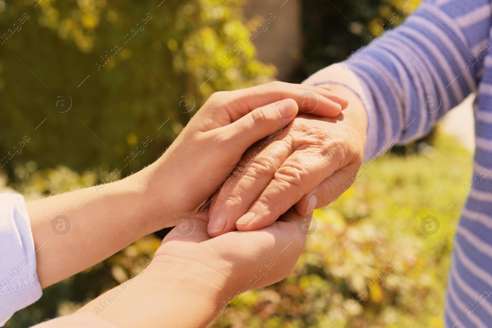 Photo of Helping hands on blurred background, closeup. Elderly care concept