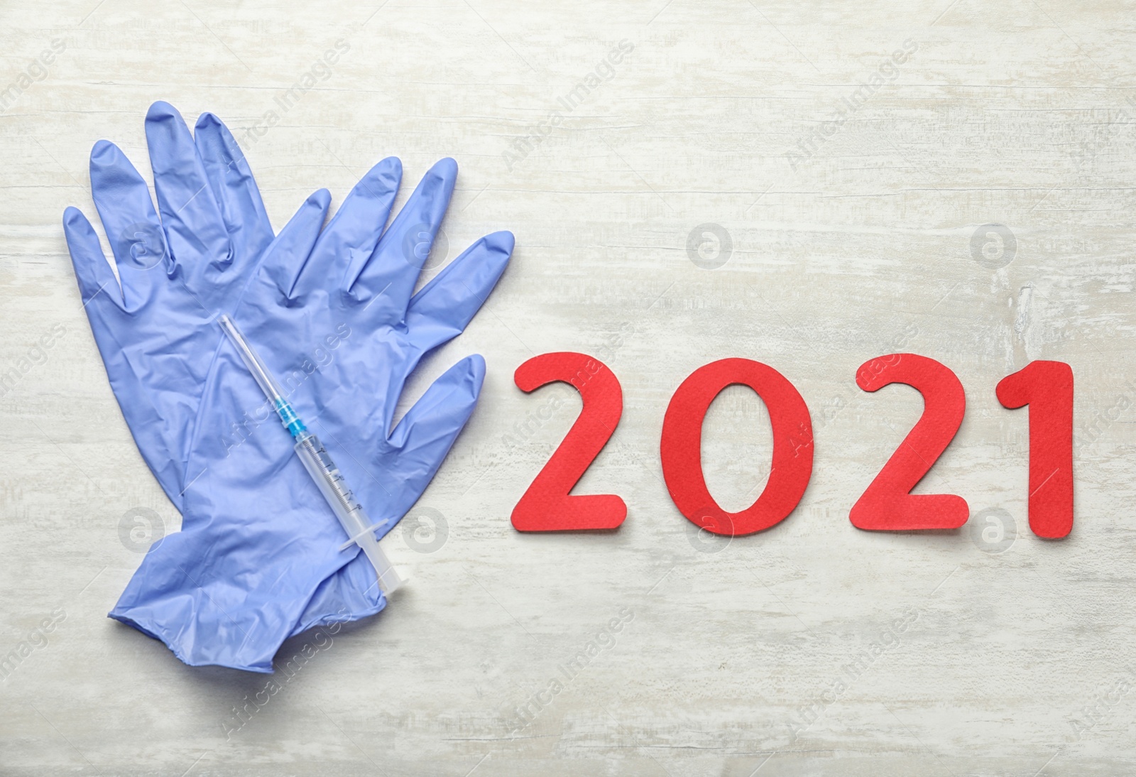 Photo of Number 2021, syringe with coronavirus vaccine and medical gloves on white background, flat lay