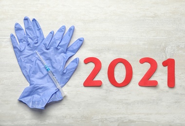 Photo of Number 2021, syringe with coronavirus vaccine and medical gloves on white background, flat lay