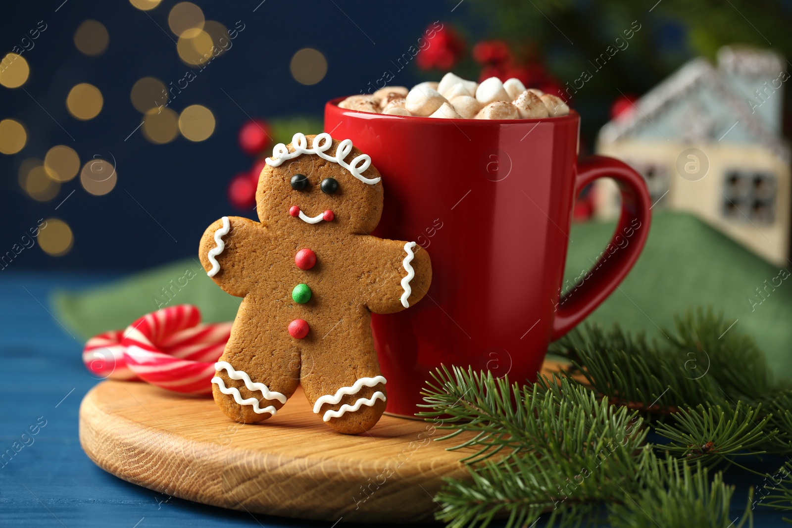 Photo of Tasty gingerbread man cookie and cocoa with marshmallows on blue wooden table, closeup