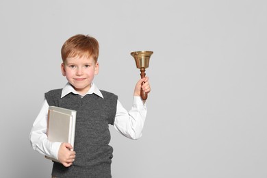 Photo of Pupil with school bell and books on light grey background. Space for text