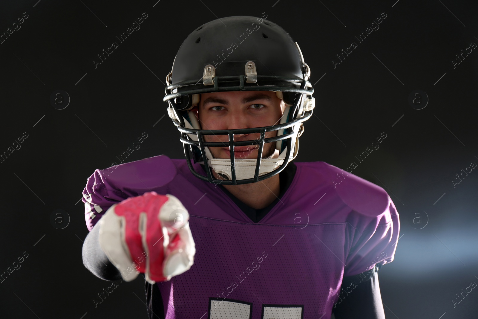 Photo of American football player wearing uniform on dark background