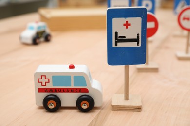 Photo of Different miniature road signs and cars on wooden table, closeup. Montessori toy
