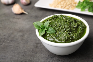 Photo of Homemade basil pesto sauce in bowl on table. Space for text