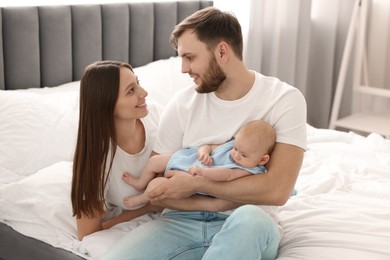 Photo of Happy family. Parents with their cute baby on bed indoors