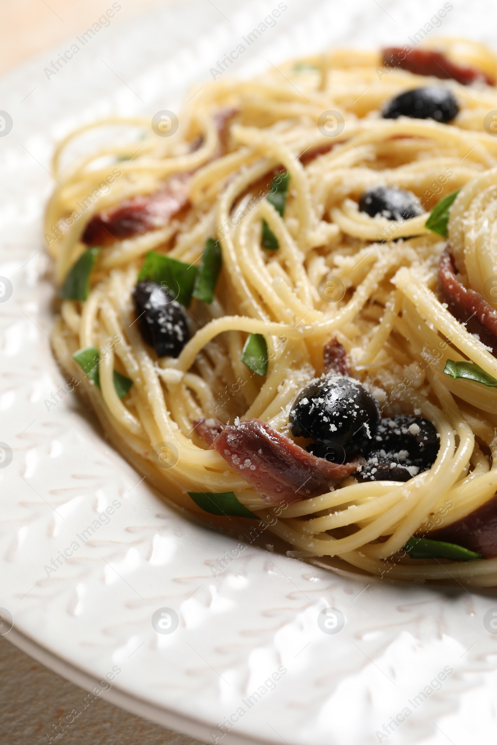 Photo of Delicious pasta with anchovies, olives and parmesan cheese on table, closeup