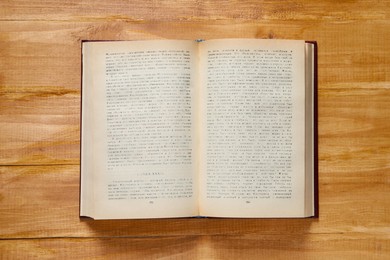 Photo of Open old hardcover book on wooden table, top view