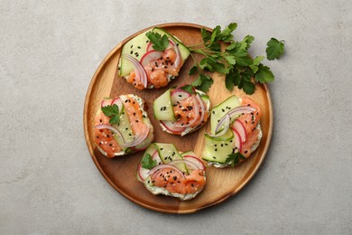 Photo of Tasty canapes with salmon served on light grey table, top view