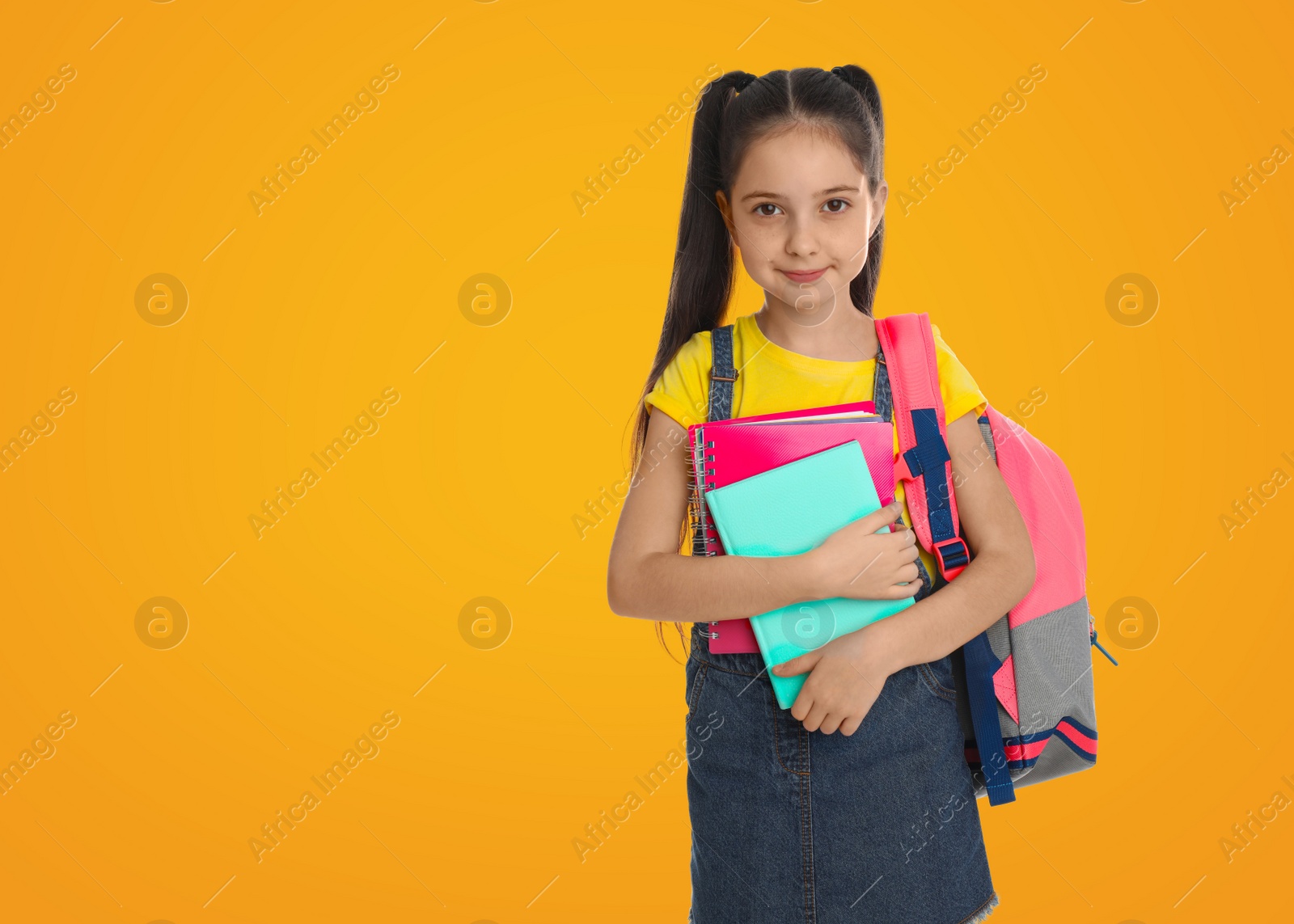 Image of Little girl with school stationery on yellow background, space for text