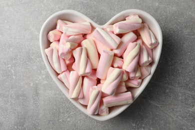 Marshmallows in heart shaped bowl on grey table, top view