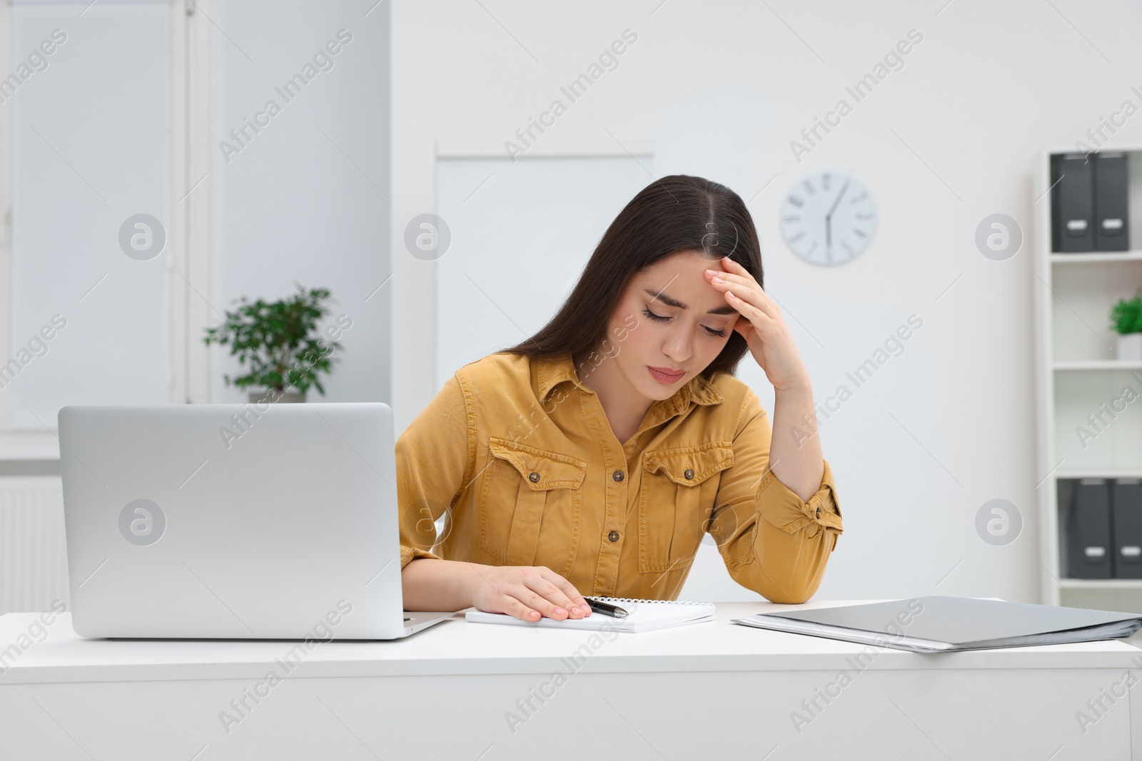 Photo of Unhappy young female intern at table in office